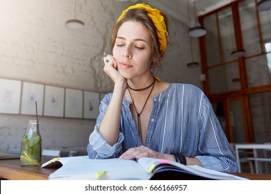 Fashionable Beautiful Talented College Girl Focusing On Home Assignment, Writing Essay, Reading Or Learning New Words, Leaning On Her Elbow And Smiling Mysteriosly, Having Thoughtful Dreamy Look