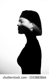 Fashionable Beauty Portrait. Black Silhouette On White Background. Girl With A Spot Of Light On Her Face. 