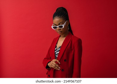Fashionable Black woman wearing classic red suit with double breasted blazer, zebra print top, trendy white frame sunglasses. Fashion studio portrait. Copy, empty space for text
				