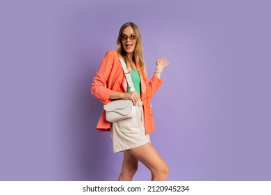  Fashionable Blond Woman With Suprice Face    In Pink Jacket Posing On Purple Background In Studio.