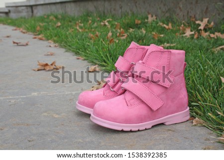 fashionable bright boots for a girl on a background of autumn leaves and green grass