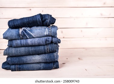 fashionable clothes. pile of jeans on a wooden background - Powered by Shutterstock