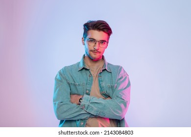 Fashionable Colorful Creative Studio Portrait Of A Handsome Young Guy With Hair And Vintage Glasses Wearing Trendy Denim Clothes With A Stylish Denim Shirt With Pink And Blue Lights. Hipster Man