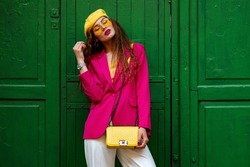 Fashionable Confident Woman Wearing Trendy Outfit With Yellow Sunglasses, Beret, Wrist Watch, Shoulder Bag, Pink Fuchsia Color Blazer, Posing Near Green Door. Copy, Empty Space For Text