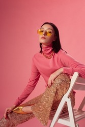 Fashionable Confident Woman Wearing Trendy Yellow Sunglasses, Pink Turtleneck Top, Sequined Flare Trousers, Golden Pointed Toe Shoes