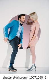 Fashionable Couple In Love Looking At Each Other While Stepping Through Hole On Grey  