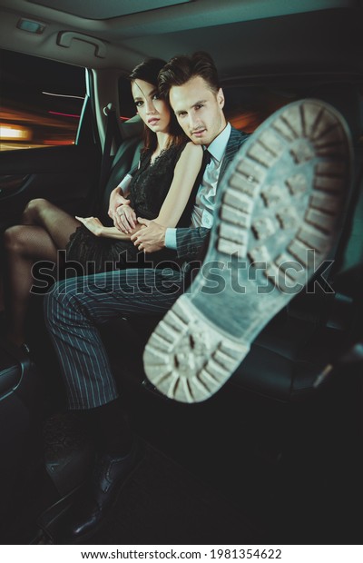 Fashionable couple of\
young people in the car. Glamorous lifestyle, night party. Night\
life in a big city.