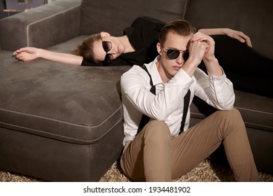 Fashionable Couple Of Young People In Elegant Clothes And Sunglasses Posing In A Luxury Apartment. Fashion Shot. Glamorous Lifestyle. 