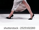 Fashionable details of a long flowing shiny skirt and black high heels