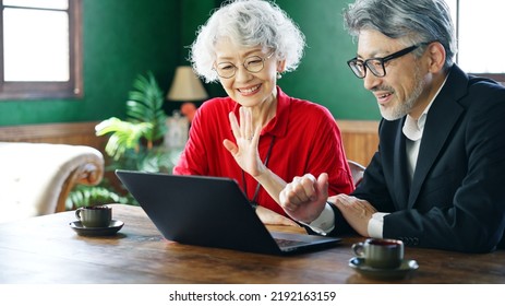 Fashionable Elderly Asian Man And Woman Talking With Video Calling In The Room.