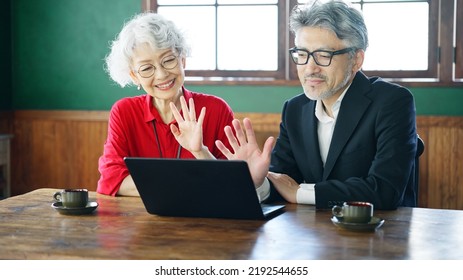 Fashionable Elderly Asian Man And Woman Talking With Video Calling In The Room.