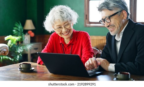 Fashionable Elderly Asian Man And Woman Using A Laptop PC In The Room.