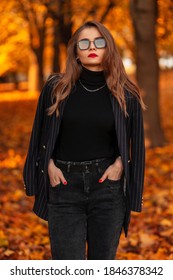 Fashionable Elegant Beautiful Woman In A Stylish Black Suit With Sunglasses Walking In The Park With Orange Colored Autumn Foliage