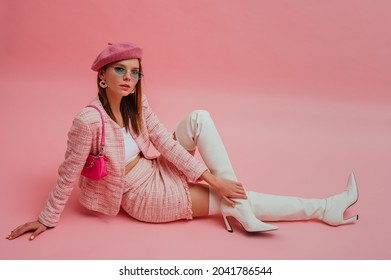 Fashionable, elegant woman wearing  beret, sunglasses, pink tweed suit with mini skirt, white leather over knee boots with high heels, posing with patent leather sholder bag. 
				Copy, empty space