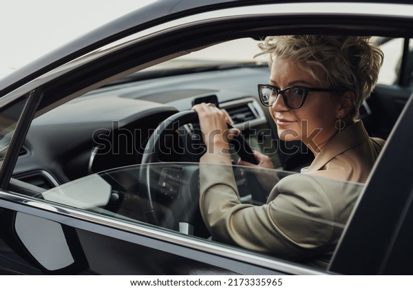 Fashionable Female Driver Looking Through the Window\
While Driving Car, Side\
View