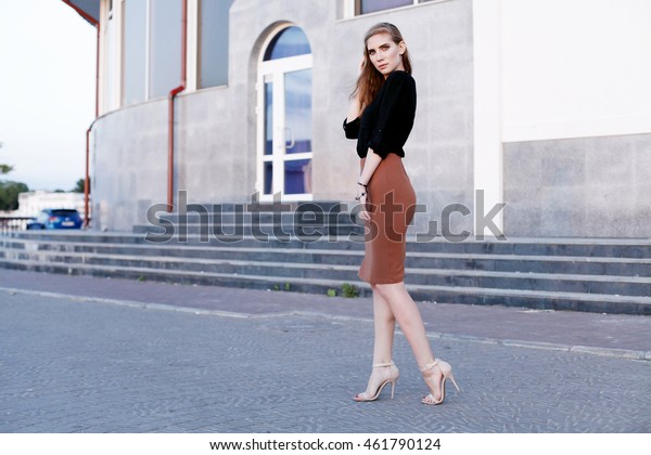 Fashionable female model in black blouse and\
pencil skirt. Autumn fashion\
outfit.