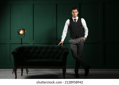 Fashionable gentleman standing near sofa in dark room - Shutterstock ID 2128958942