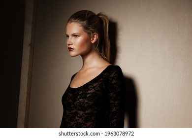 Fashionable Girl In Black Bodysuit With Tight Hair In The Ponytail, Posing In The Studio, Looking At The Side.