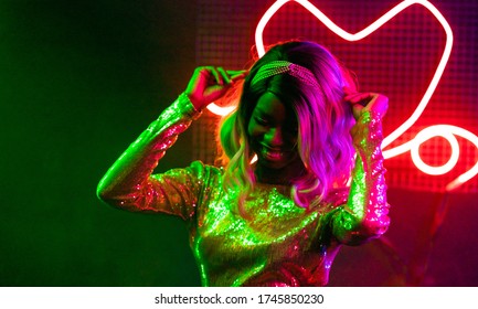 Fashionable Girl Dancing In Night Club. Cheerful African American Woman Dancing Among The Bright Neon Lights. Party Concept. Lifestyle Concept.