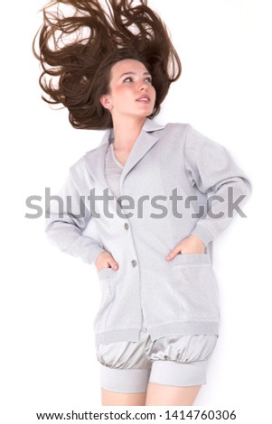Fashionable girl posing in a silver jacket on a white background