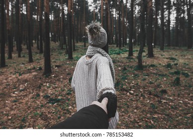 Fashionable girl walking in nature wood forest environment holding her boyfriend for hand. 