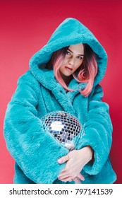 Fashionable Glamour Girl Posing In Blue Fur Coat With Disco Ball, Isolated On Pink