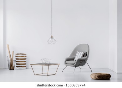 Fashionable Grey Colored Armchair With Pillow Next To Industrial Coffee Table In Chic Living Room Interior