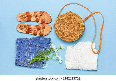 Fashionable handmade natural organic rattan bag, leather sandals, denim shorts, white blouse on blue background flat lay. Copy space, top view. Rattan handbag, ecobags from Bali. Eco-bag concept. - Powered by Shutterstock