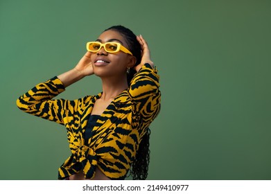 Fashionable Happy Smiling Black Woman Wearing Trendy Yellow Rectangle Sunglasses, Animal, Tiger Print Blouse, Posing On Green Background. Copy, Empty Space For Text