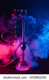 Fashionable hookah with a cloud of smoke on a black background with red and blue glow