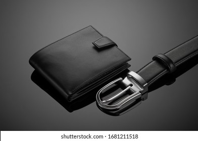 Fashionable leather men's wallet and belt on a black background