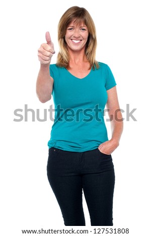 Fashionable middle aged blonde showing thumbs up sign to the camera.
