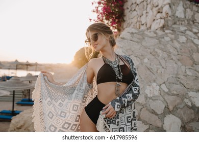 Fashionable Model Posing On Beach, Girl Wearing Sexy Black Bikini, Swimsuit With Hight Waist, Cardigan, Cape With Ornaments , Beautiful Beach, Flowers, Rock On Background.