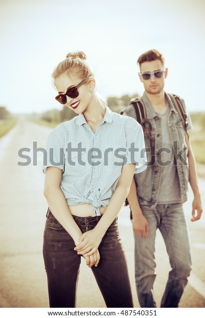 Fashionable models wearing jeans\
clothes posing on a highway. Denim style. Sepia, retro\
styled.
