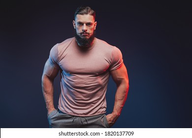 Fashionable and muscular with beard guy dressed in shirt and pants posing dark background. - Shutterstock ID 1820137709