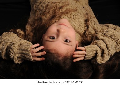 Fashionable Portrait Of A Girl 5 Years Old In A Knitted Sweater On A Black Background