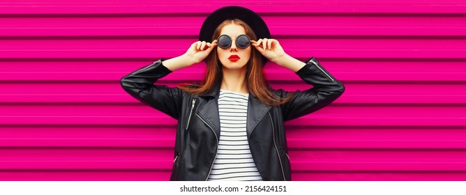 Fashionable Portrait Of Stylish Woman Model Posing Wearing Black Rock Biker Jacket And Round Hat On Pink Background, Blank Copy Space For Advertising Text