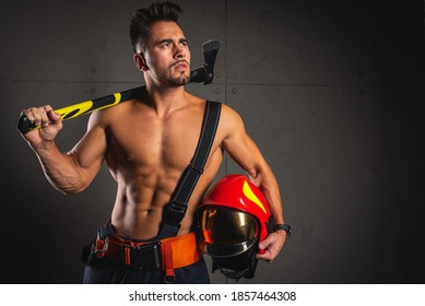 Fashionable Portrait Of A Young Man In Fire Equipment On A Black Studio Background. Fireman In A Dark Uniform.