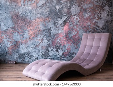 Fashionable Purple Lounge Chair Stands Against A Concrete Wall