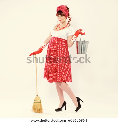 Fashionable redhead pregnant woman in pin up style with bucket, broom and rubber gloves