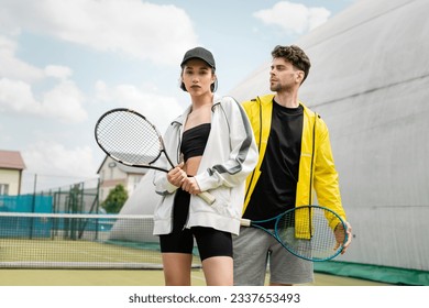 fashionable sportswear, man and woman holding tennis rackets on court,  sport and style - Shutterstock ID 2337653493