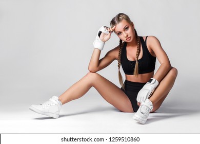 Fashionable studio portrait of an attractive girl in boxing gloves and black lingerie on a white background.