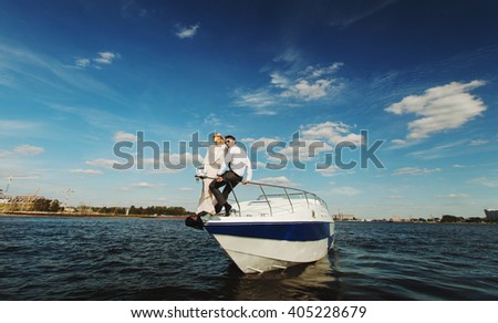 Fashionable stylish couple on vacations posing on yacht on blue sky with clouds and sea landscape background in daylight