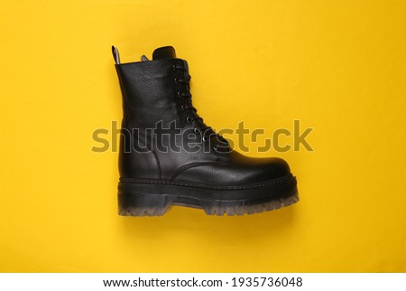 Fashionable stylish leather female boot on a yellow background. Top view