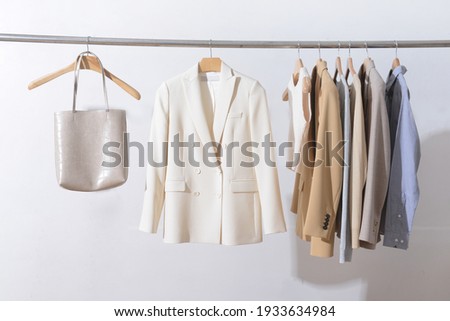 Fashionable white suit with clothing ,sweater,jacket  handbag are hanging on Clothes Hanger,