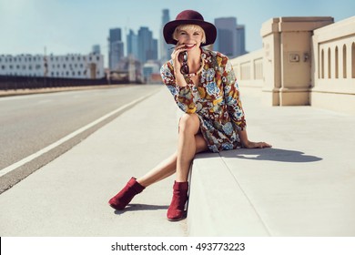 Fashionable Woman In A Hat, Flower Pattern Dress, Sunglasses, Boots, Walking In The Street. Fashion Autumn Photo, Accessories