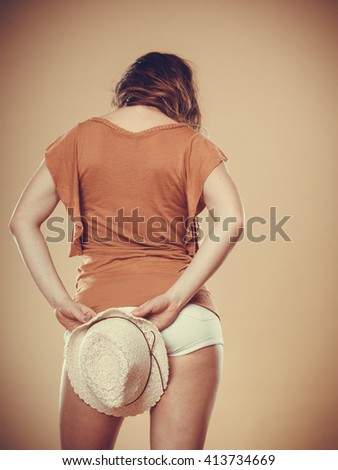 Fashionable woman holding hat behind back. Summer fashion. Rear view. Holidays vacation.