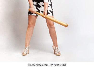 Fashionable woman holding a wooden baseball bat in her hands and showing feminine confidence - Powered by Shutterstock