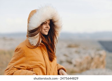 Fashionable woman in orange parka with fur hood looking at camera in winter outdoor setting - Powered by Shutterstock