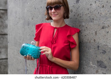 Fashionable Woman In Red Dress Holding Leather Snakeskin Python Bag. Elegant Outfit. Close Up Of Purse In Hands Of Stylish Lady. Model Posing Near The Swimming Pool.